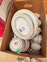 Boxed set showing oval platters, stack of plates, lidded teapot and assorted cups