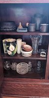 Cabinet shelves showing majority of glass, ceramic and stoneware items