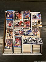 Four columns of hockey cards in storage box with sample cards on top showing various players and team logos