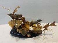 Full view of amber resin squirrel sculpture on black base showing leaves, squirrels and sticker