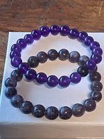 Two amethyst bead bracelets on white box