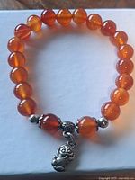 Full view of bracelet showing carnelian beads, silvertone spacers and charm