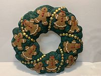 Front view showing green ceramic wreath with gingerbread figures and gold beads