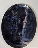 Front view of oval porcelain plate showing artwork and gold rim