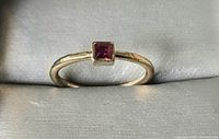 Front view of gold-tone ring with square red stone