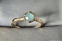 Front view of gold-tone ring with light blue cabochon