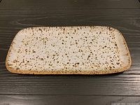 Top view of rectangular cream ceramic platter with brown speckles and rim
