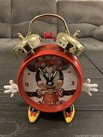 Front view showing Minnie Mouse dial, red case, gold bells, glove hands, shoe feet