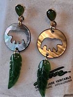 Front view of both earrings showing jade tops, abalone discs with bear cut-out, and carved jade leaves