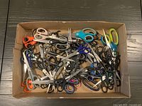 Box containing large assortment of scissors in various colors and sizes