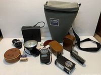 Group view of all items including GE light meter, Vivitar flash, Nikkorex accessory, leather cases, Serratus bag, spare bulbs and cord