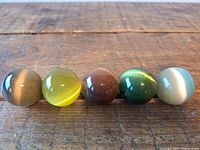 Five cat's eye stone spheres lined up on wooden surface