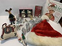 Group shot of all items including cookbook, pillow, hat, figurine, ornaments and spoon