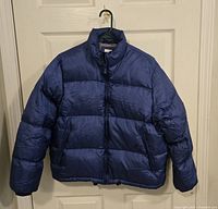 Full view of blue puffer jacket on hanger