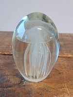 Front view of egg-shaped glass paperweight displaying internal jellyfish figure