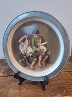 Front view of plate on stand showing artwork and metal rim