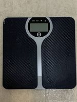 Top view of digital bathroom scale showing black textured surface, silver accent, LCD screen and Weight Watchers logo