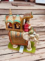 Full view of carved and painted stone elephant with howdah on plinth base