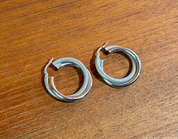 Pair of textured double hoop sterling silver earrings on wooden surface