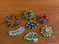 All seven brooches laid out on wood surface