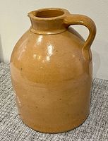 Front view of tan stoneware jug showing body shape and handle