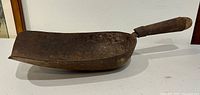Side profile showing depth and curvature of iron scoop with attached wooden handle