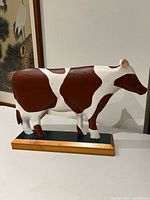 Full side view of carved wooden cow on base
