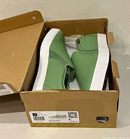 Pair of dusty green Puma slip-on shoes inside original box