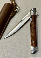 Folding knife partially open next to leather sheath