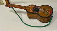 Front view showing guitar shape, painted decorations, green strap