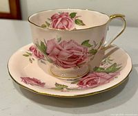 Teacup on saucer showing rose pattern and gold trim