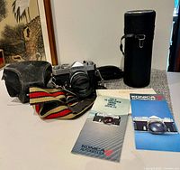 Full lot showing camera, lens, strap, manuals, hard case, zip bag