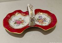 Top view showing dual dishes, handle, red border, floral centers, gold trim