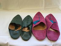 Both pairs of Egyptian pointed-toe slippers—green leather and purple suede—side by side