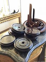 Stacked round wooden pedestals with three folding plate stands in background