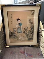 Full view of framed silk painting standing in chair