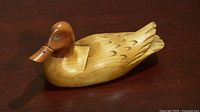 profile of carved wooden duck on dark surface