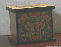 Three-quarter view of bentwood box showing painted Haida design on side and lid