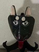 Front view of black wooden cat mask on stand