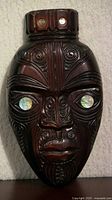 Front view of carved tiki mask showing details and paua shell inlays