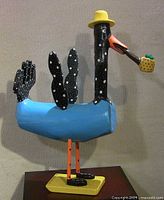 Full view of painted wood bird sculpture on base