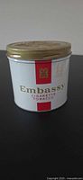 Front view of Embassy cigarette tobacco tin with lid attached