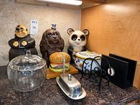 Group shot showing all items: three cookie jars, biscotti jar, cheeseburger bookend, glass pumpkin bowl, butter dish, two napkin holders