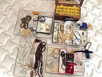 Overview of trays with necklaces, brooches, earrings, rings, watches, wooden chest
