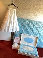 Wedding petticoat on hanger beside boxed gown and hat box