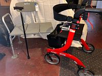Overall lot showing red Drive Nitro rollator, grey shower chair, black folding cane