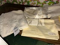 Stack of folded ivory and pale yellow tablecloths showing damask and satin textures