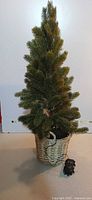 Full view of artificial pine tree in wicker basket with battery pack
