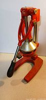 Front view of red Palm Restaurant manual juicer with lever and base