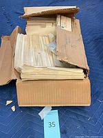 Damaged cardboard box filled with stacked yellowed papers